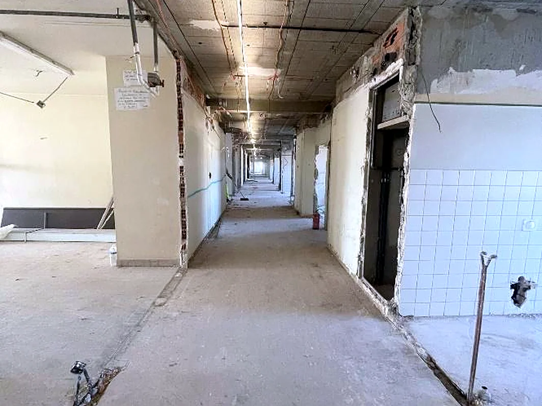 Couloir du 4e étage de l'hôpital de la Timone après curage : réseaux apparents, sols nus